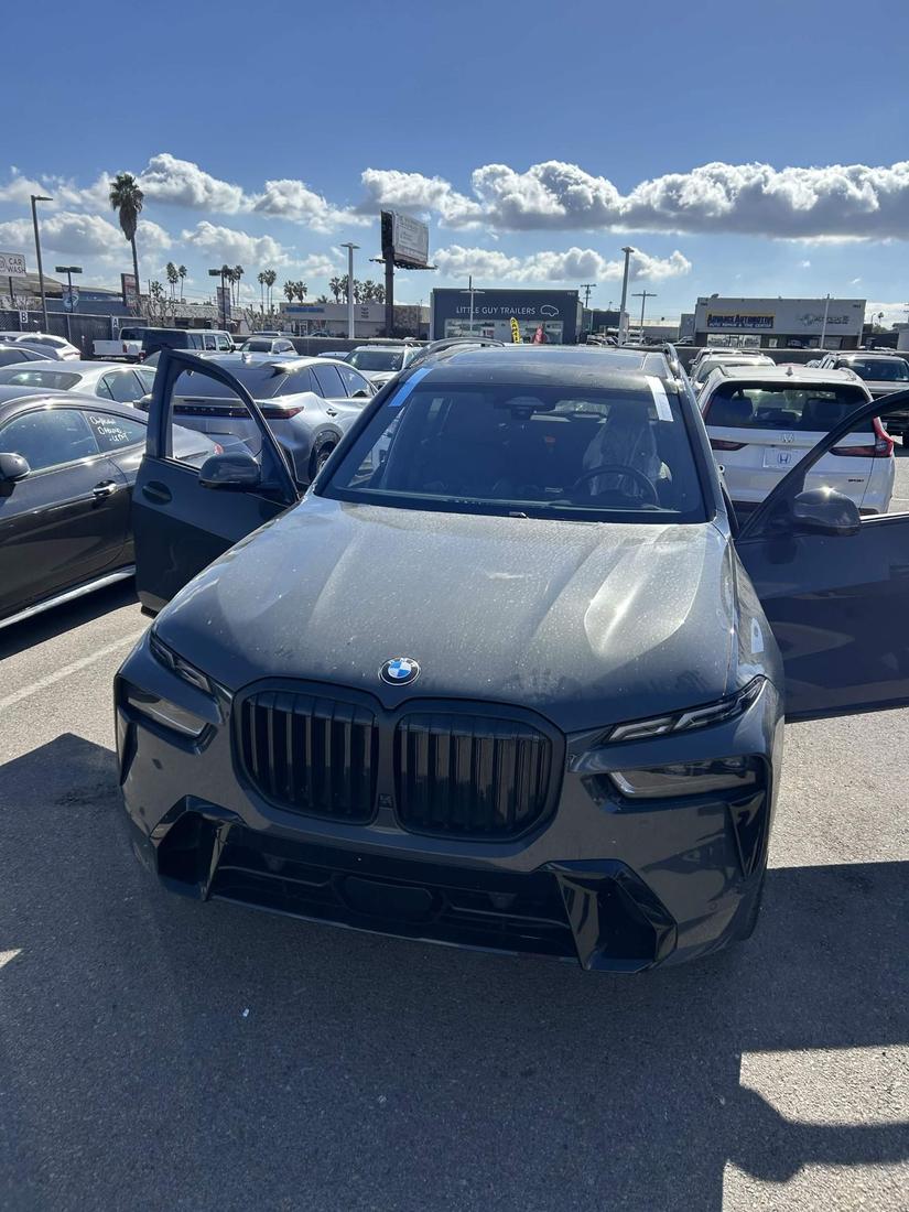 BMW X7 with a newly replaced windshield, tape strips securing it during installation